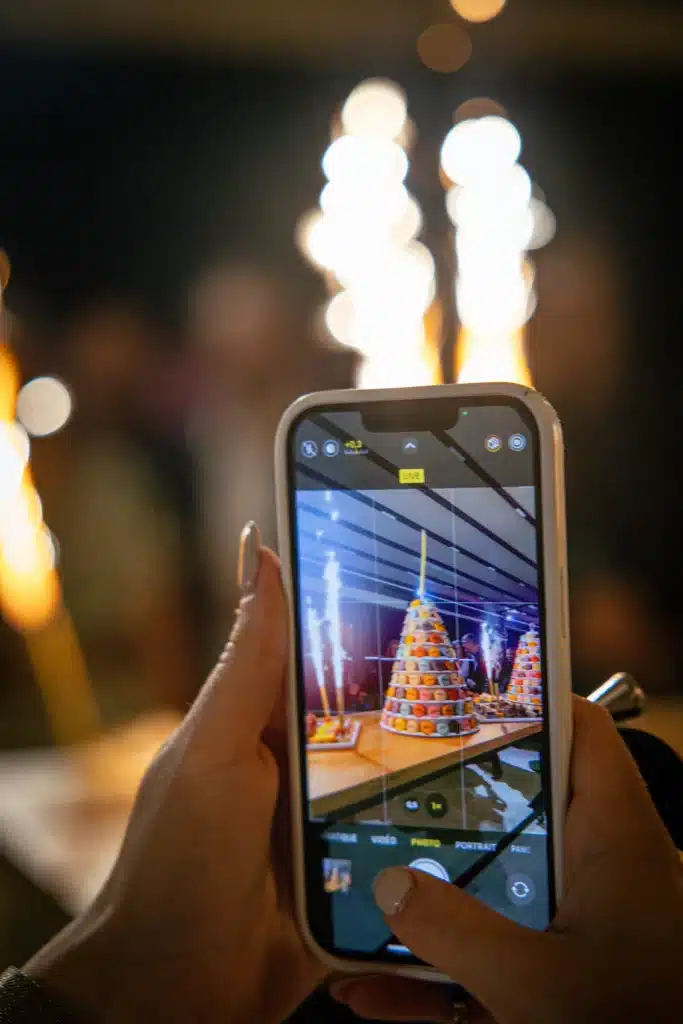 La photo montre un téléphone qui prend en photo le gâteau d'anniversaire